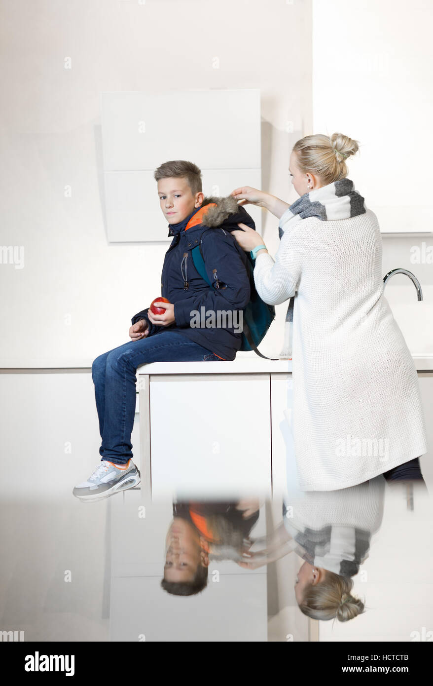 Mother preparing his son for school in kitchen . Mom and Son Eating Togetherness Cheerful Concept Stock Photo