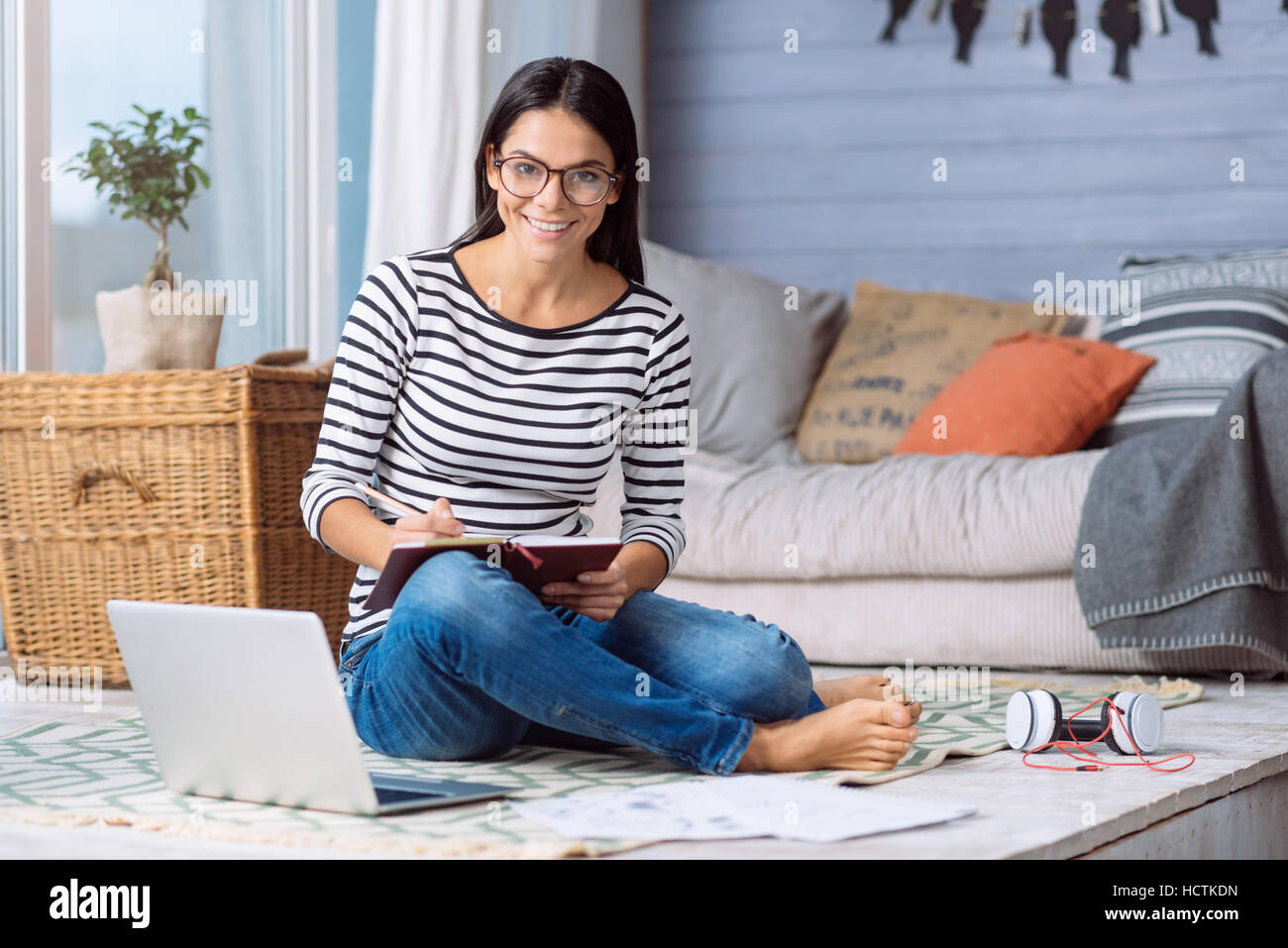 Smiling young woman writing in her notebook at home Stock Photo - Alamy