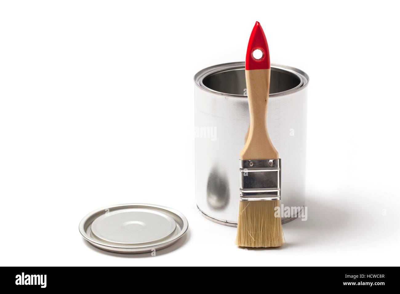 Brush leaning on an open blank metallic tin paint can isolated on white. Stock Photo
