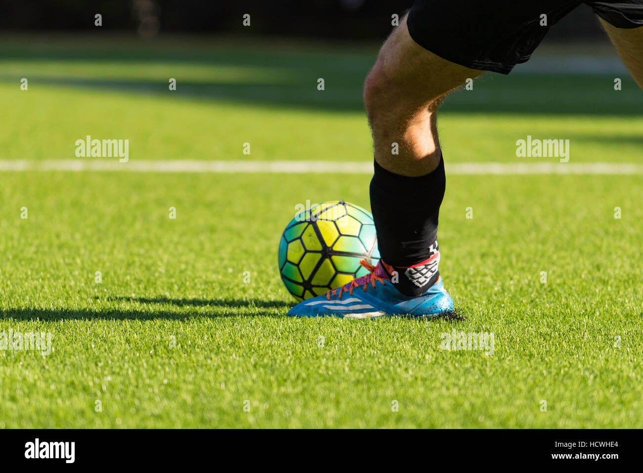 A youth lines up to kick a soccer ball on an astro turf soccer field Stock Photo