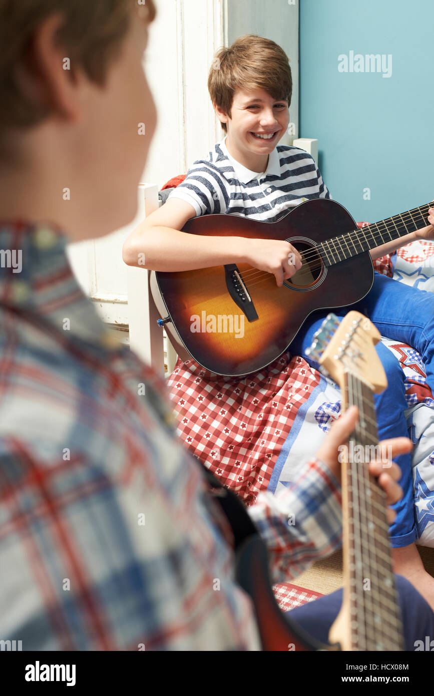 Boys In Bedroom Playing Guitars Together Stock Photo