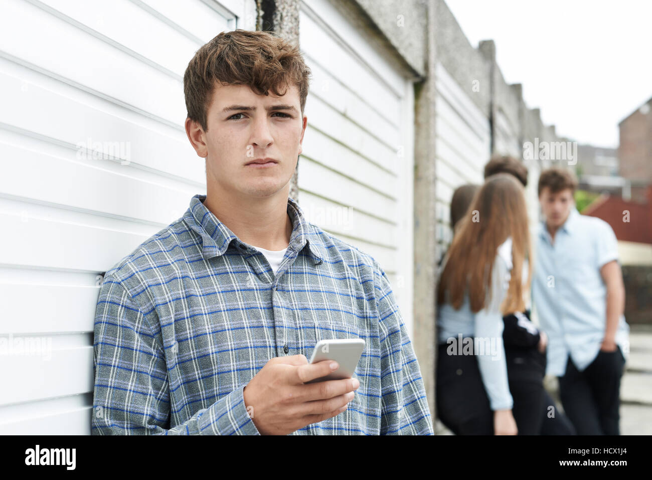 Teenage Boy Using Mobile Phone In Urban Setting Stock Photo