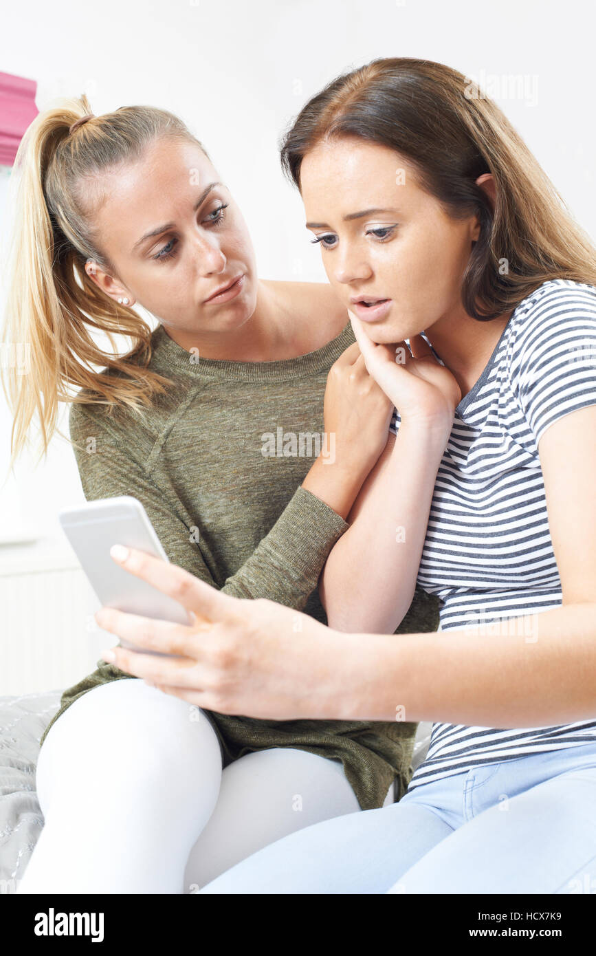 Teenage Girl With Friend Being Bullied By Text Message Stock Photo