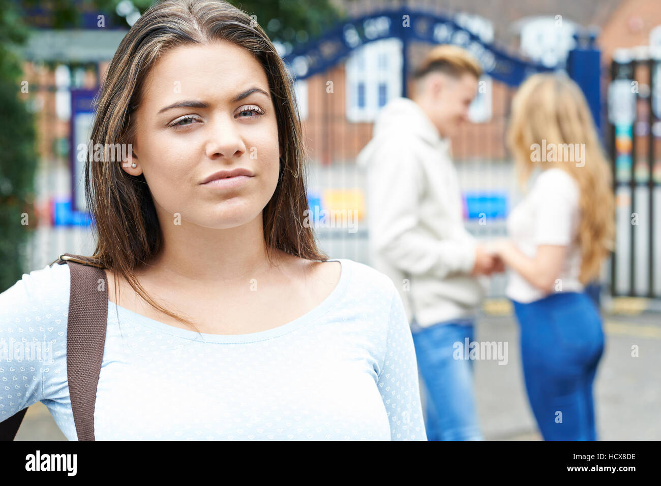 Teenage Girl Jealous Of Young Couple Outside School Stock Photo