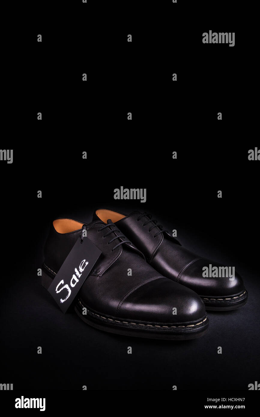 Sale sign. Black oxford shoes on black background. Back view. Copy