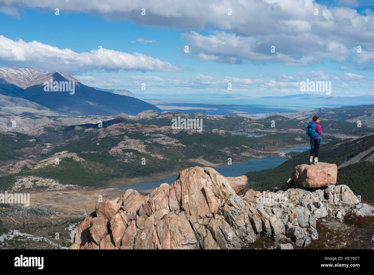 A woman takes a break from hiking the trail in El Chalten National Park to take in the view, Lake Vied, Patagonia, Argentina Stock Photo