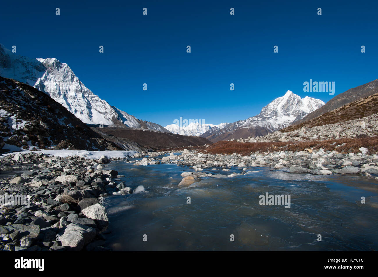 Icy meltwater flows down the Chekhung valley with views of Ama Dablam to the left and Taboche to the right, Khumbu Region, Nepal Stock Photo
