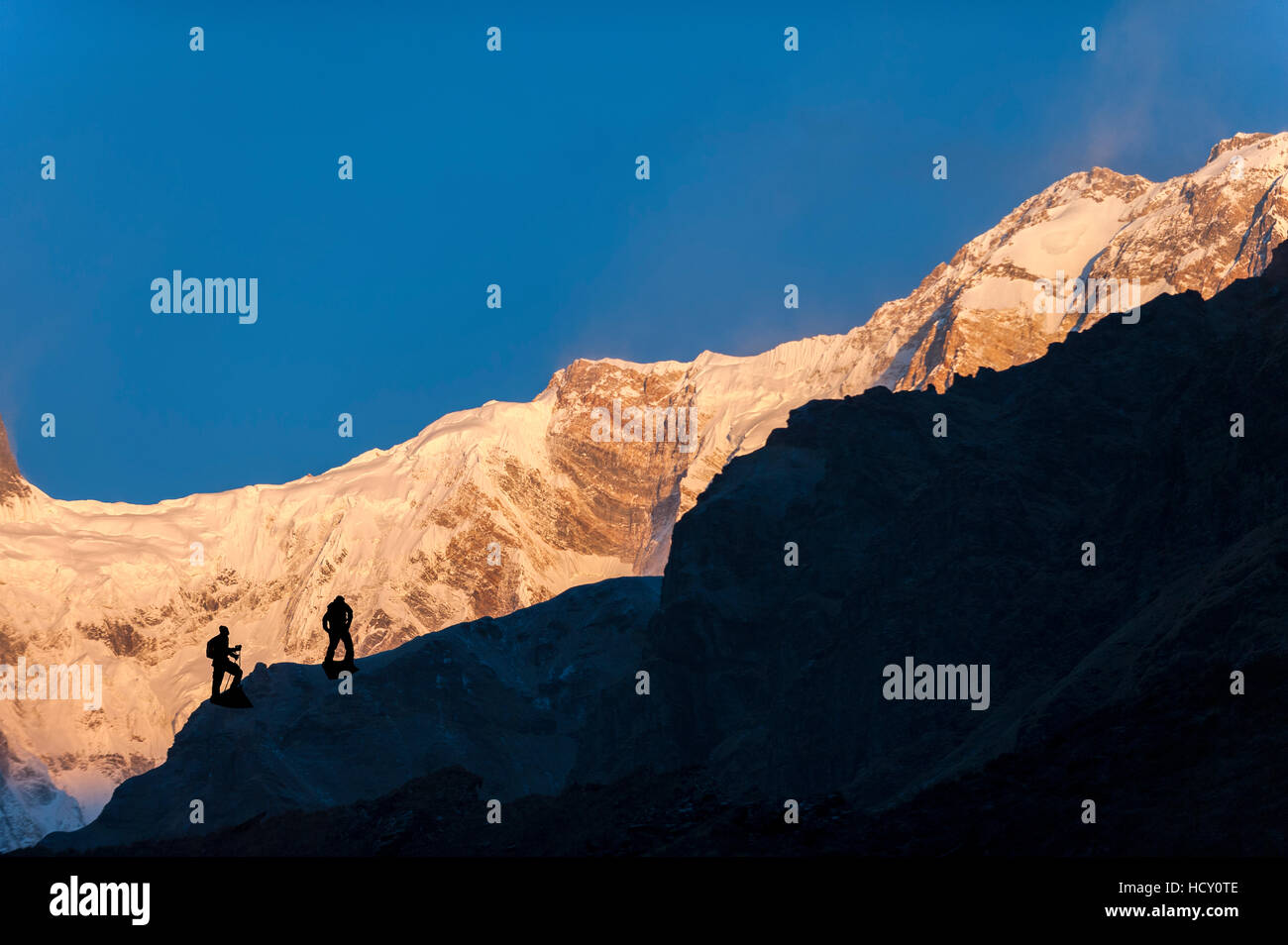 Trekkers climb to the top of the lateral moraine beside the Annapurna glacier to get a better view of Annapurna 1, Nepal Stock Photo