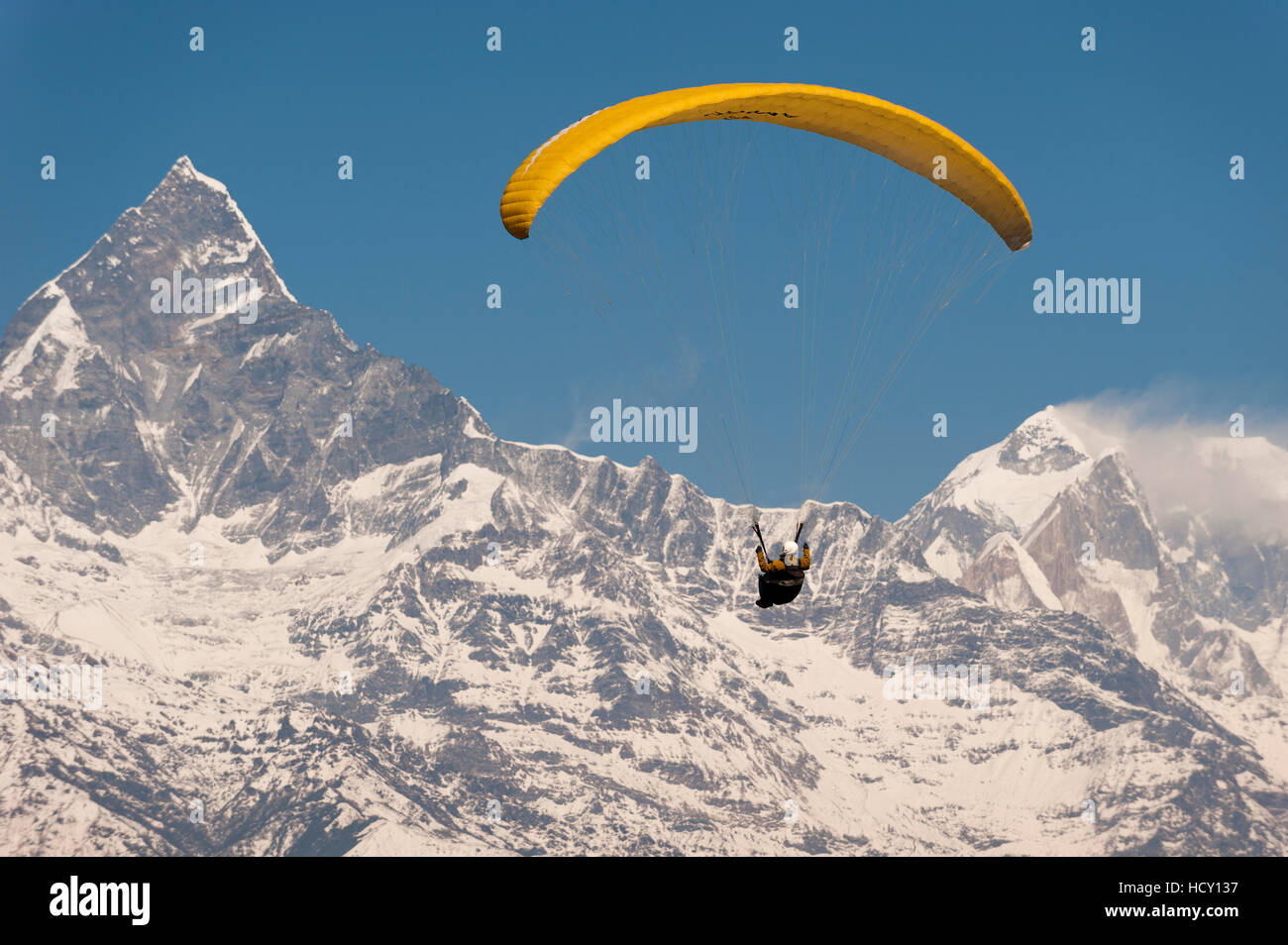 A paraglider carves a turn with views of Machapuchare (Fishtail mountain) in the distance, Nepal Stock Photo
