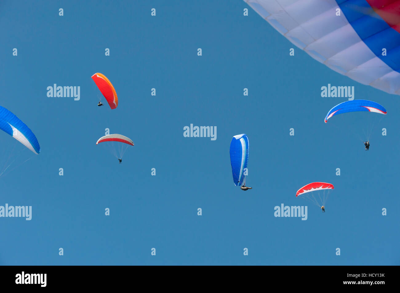 Flying on the thermals, a group of colour coordinated paragliders above Pokhara, Nepal Stock Photo