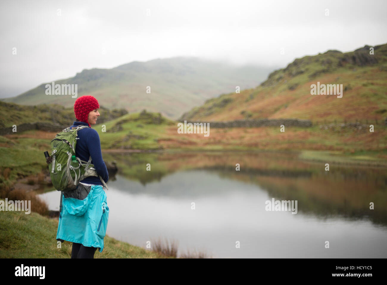 A woman looks out over Alcock Tarn near Grasmere, Lake District National Park, Cumbria, UK Stock Photo