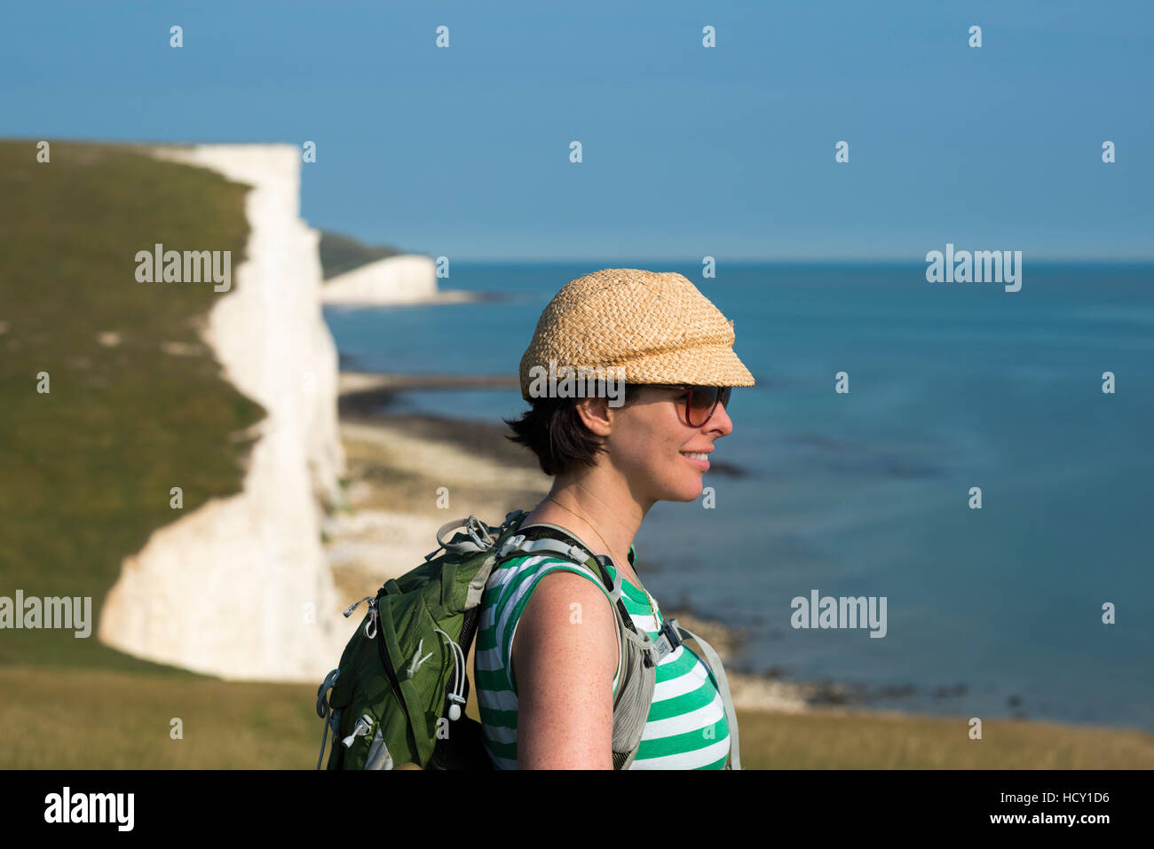 A woman looks out over the cliffs near Beachy Head with views of the Seven Sisters, South Downs National Park, East Sussex, UK Stock Photo