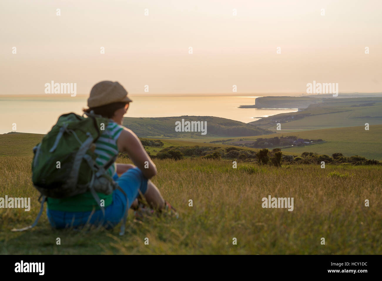 A woman looks out to sea near Beachy Head with views of the Seven Sisters coastline, South Downs National Park, East Sussex, UK Stock Photo