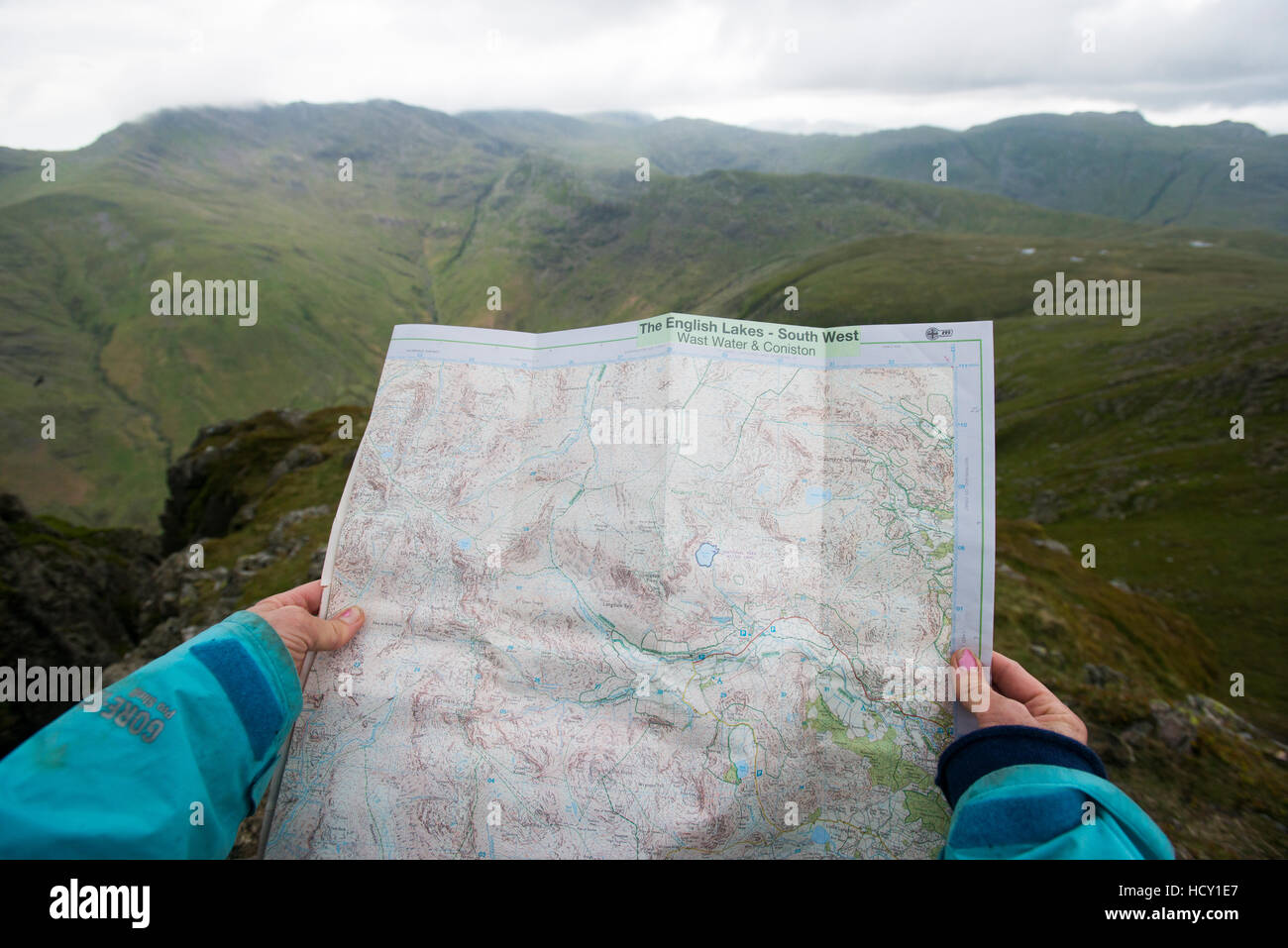 A woman checks her map while looking towards Great Langdale valley from the Langdale Pikes, Lake District, Cumbria, UK Stock Photo