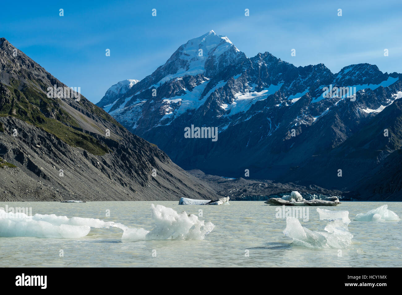 Icebergs float in a cold lake with a large snow covered mountain, South Island, New Zealand Stock Photo