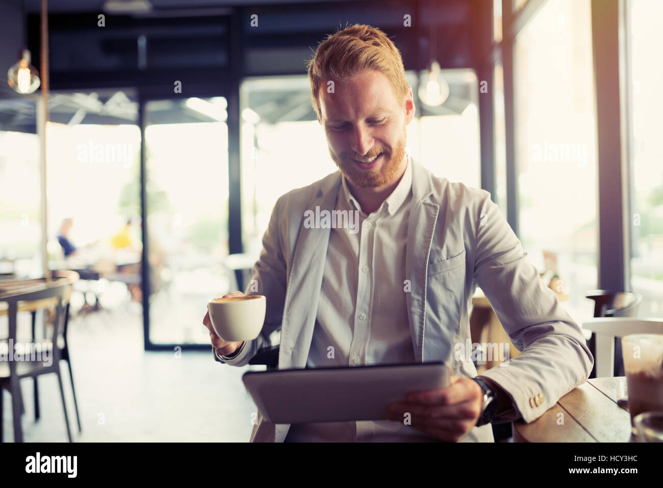Busy businessman on coffee break using tablet Stock Photo