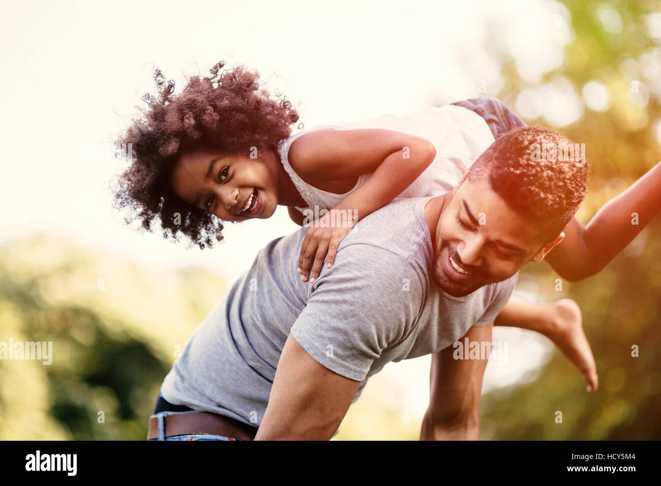 Father carrying daughter on back outdoors Stock Photo