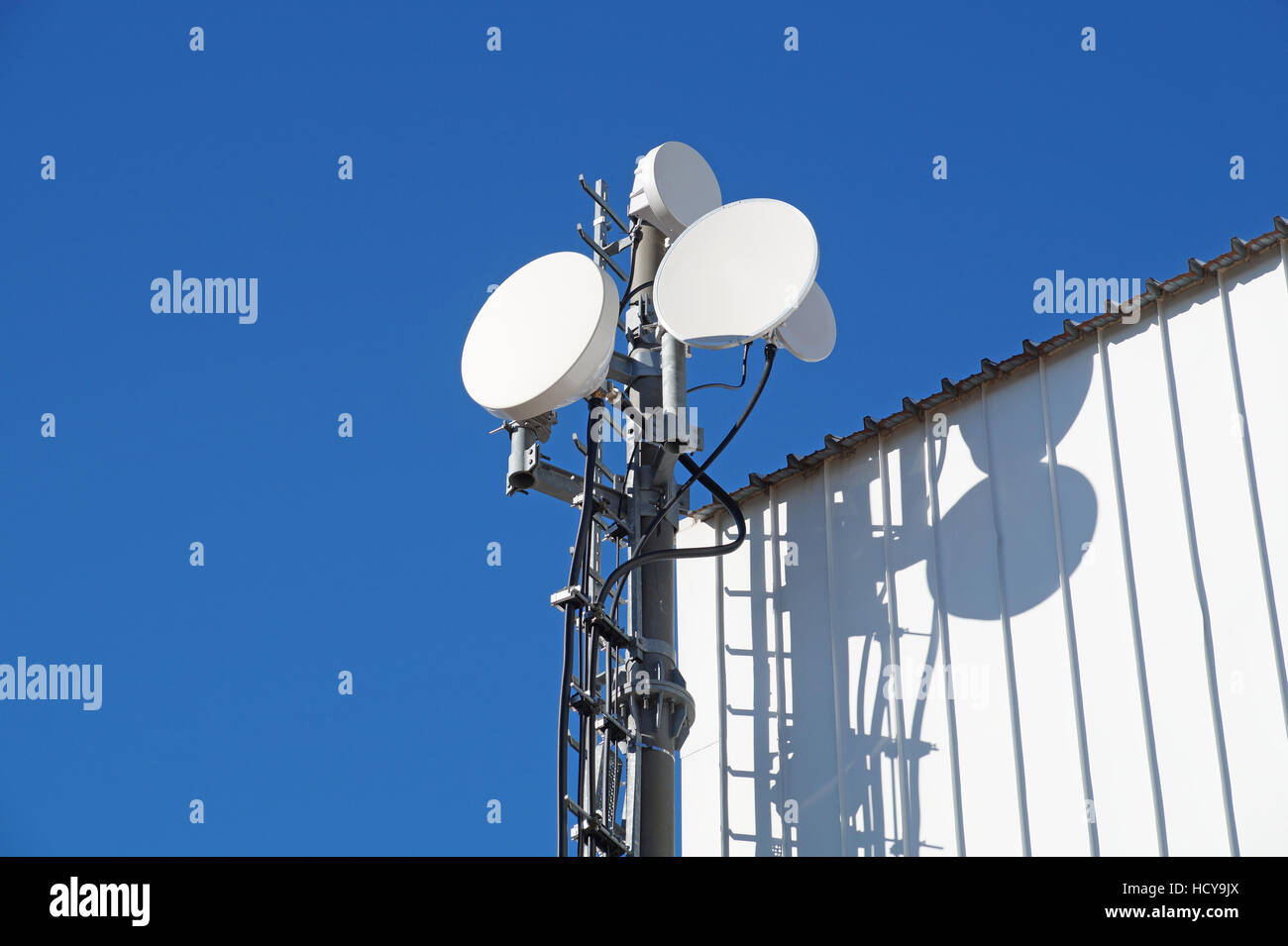 Telecommunication towers with TV antennas and satellite dish on clear blue sky Stock Photo