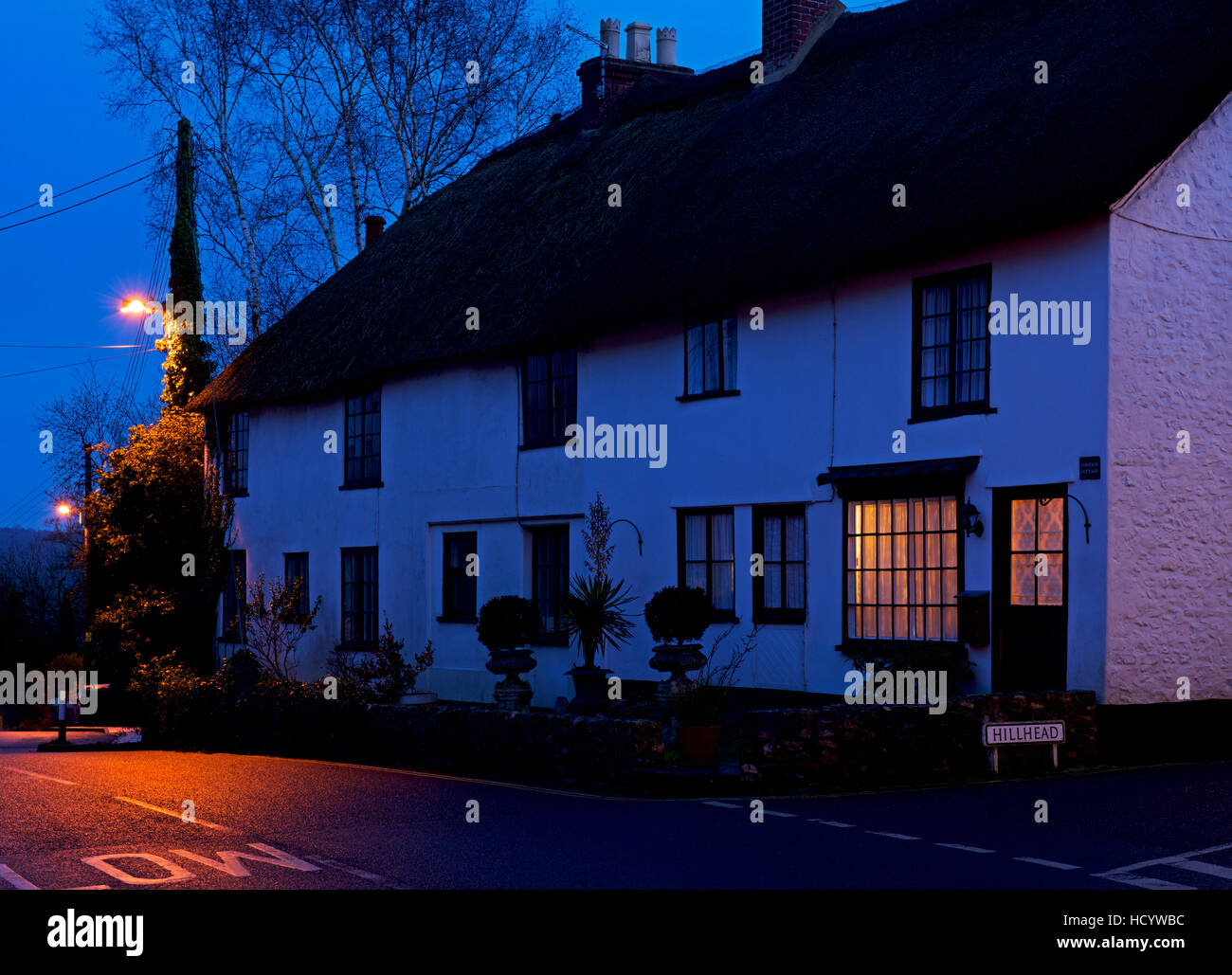 A light in the window of a thatched cottage in Colyton, Devon, England