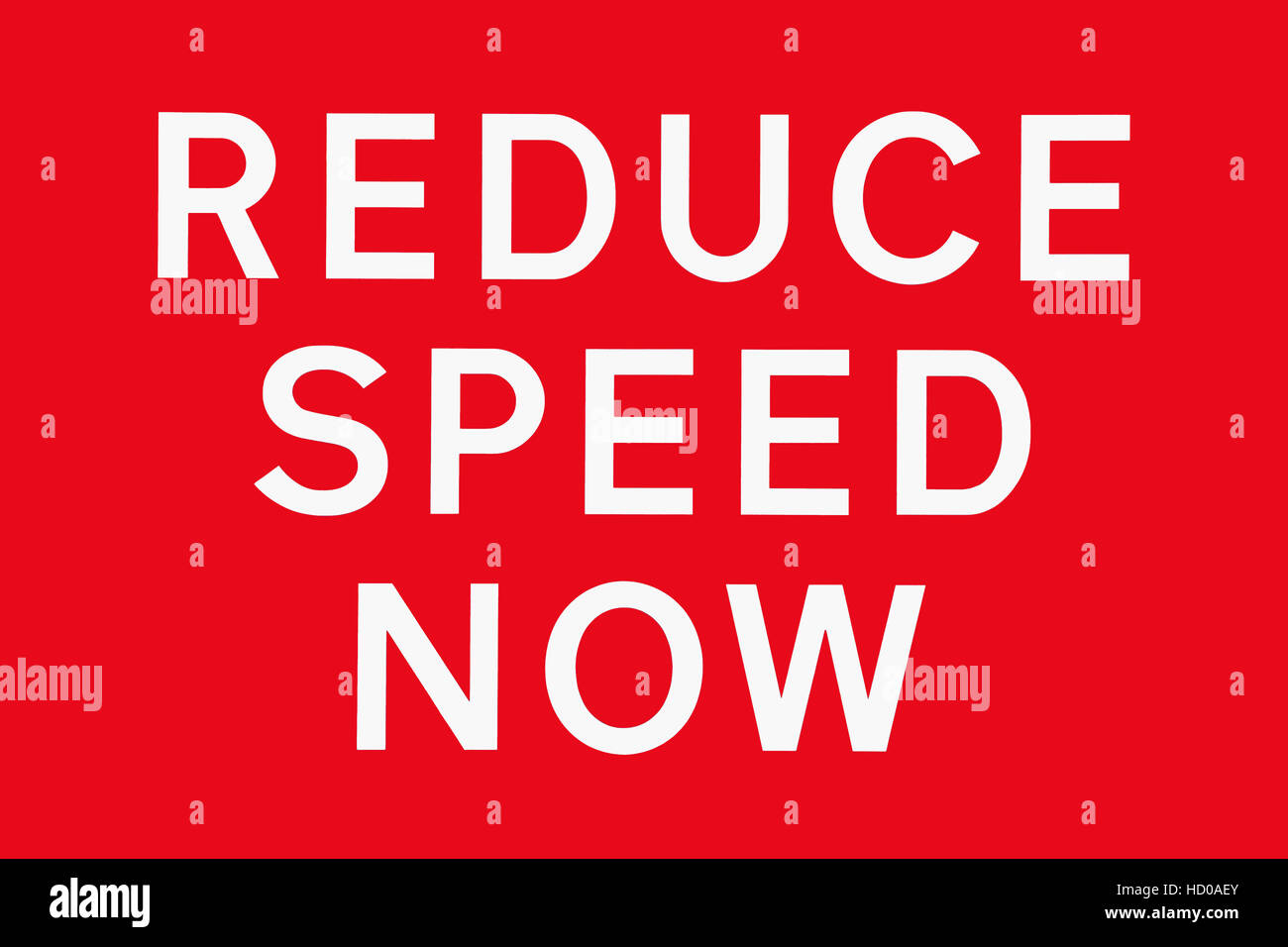 White text on red background REDUCE SPEED NOW, road signs in the UK, symbol for dangerous road Stock Photo