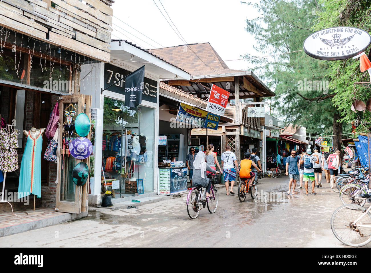 Cyclists and tourists walking down the main street on Gili Trawangan past the shops and clothing boutiques Stock Photo