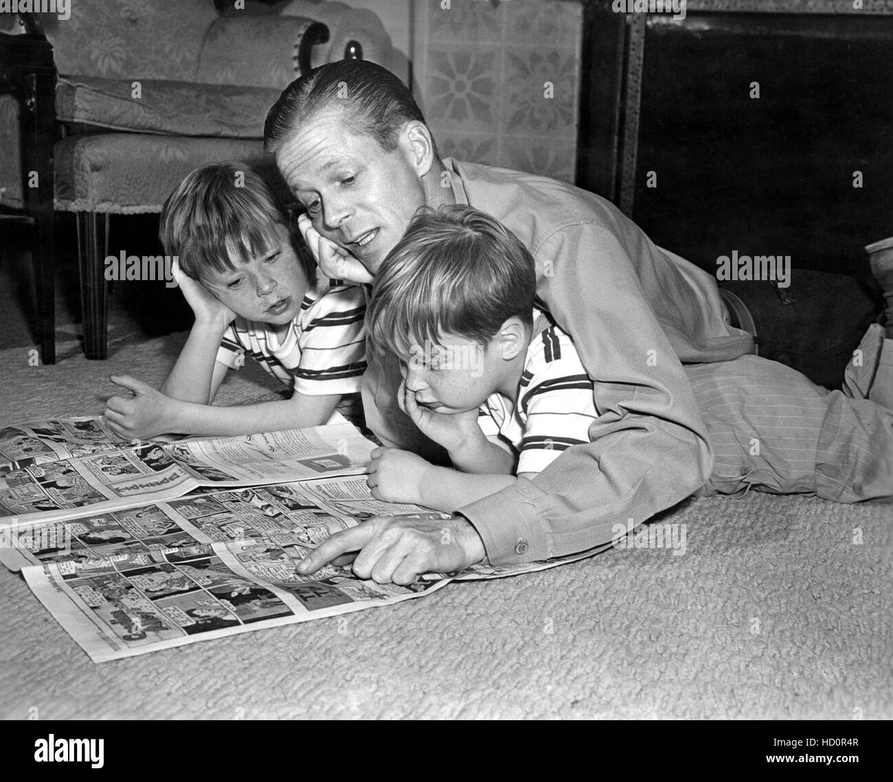 Dan Duryea (center) reading comics with sons Peter Duryea (right) and Richard Duryea (left), 1947 Stock Photo