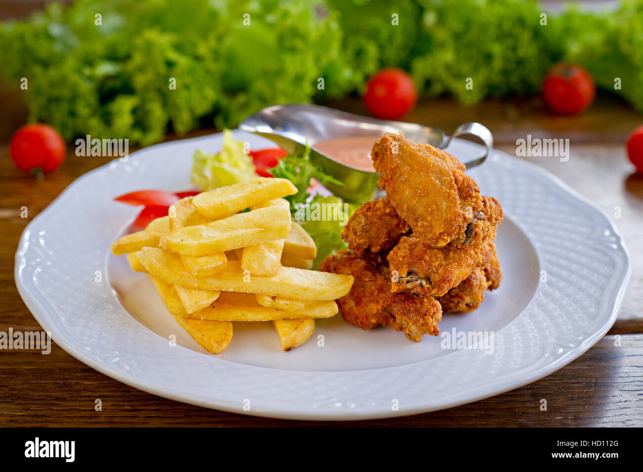 Gourmet Appetizing Chicken and Fries Meal on a White Plate with Fresh Lettuce, tomatoes slice, ketchup sauce. Stock Photo