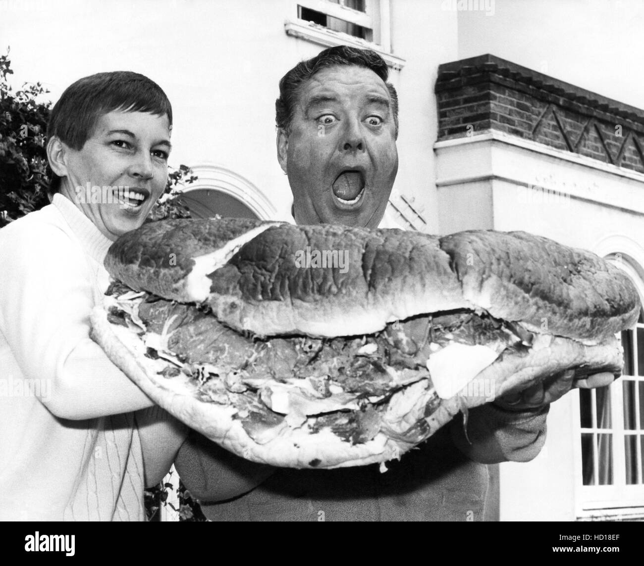 Jackie Gleason, right, tucks into a big, disgusting sandwich outside