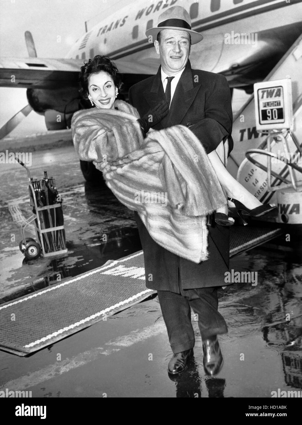 John Wayne, carrying his second wife, Esperanza Bauer, over a rainy