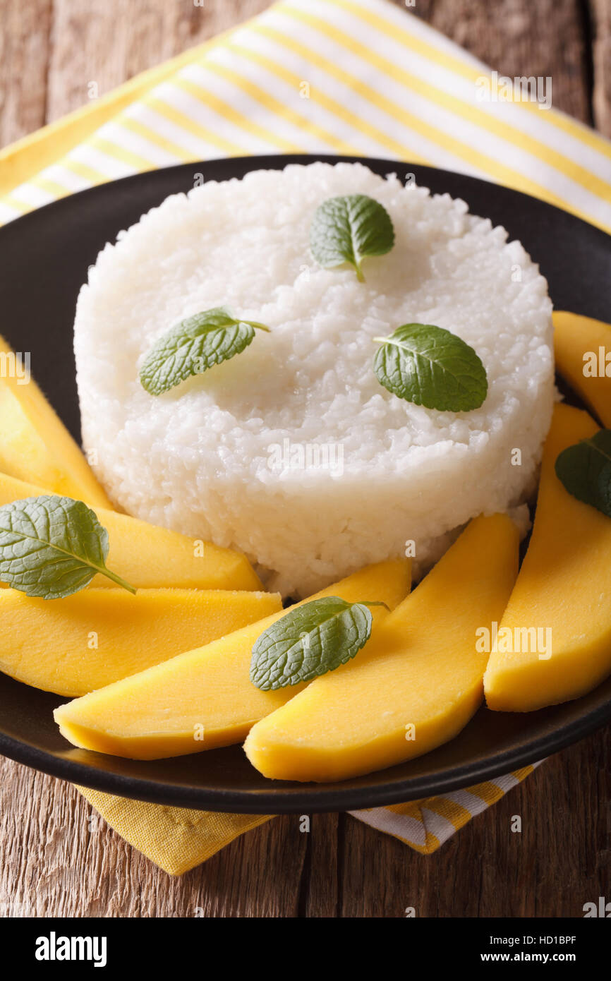 Glutinous rice with ripe mango close-up on a plate on the table. Vertical Stock Photo