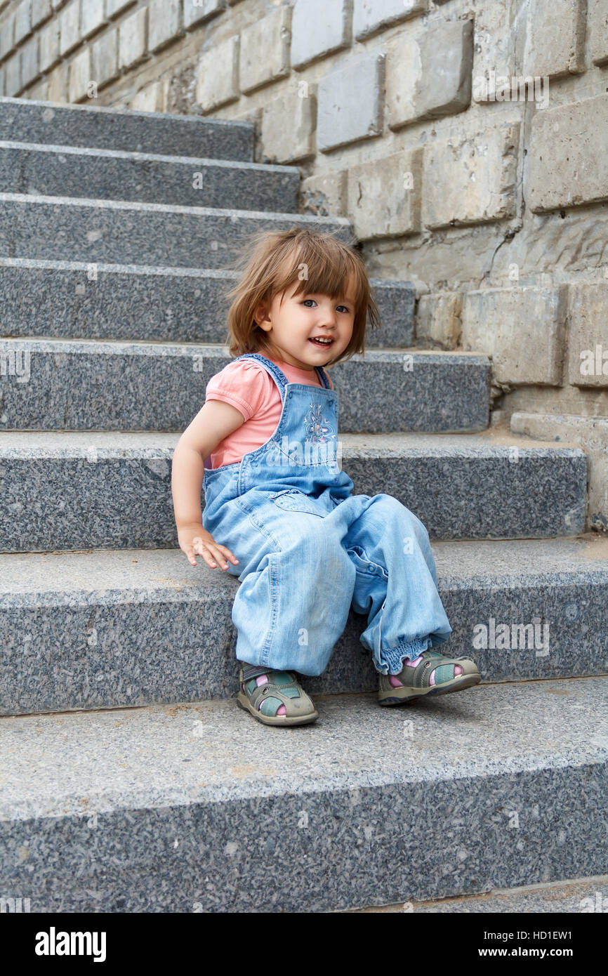 Baby girl in blue clother sitting on the stairs Stock Photo - Alamy