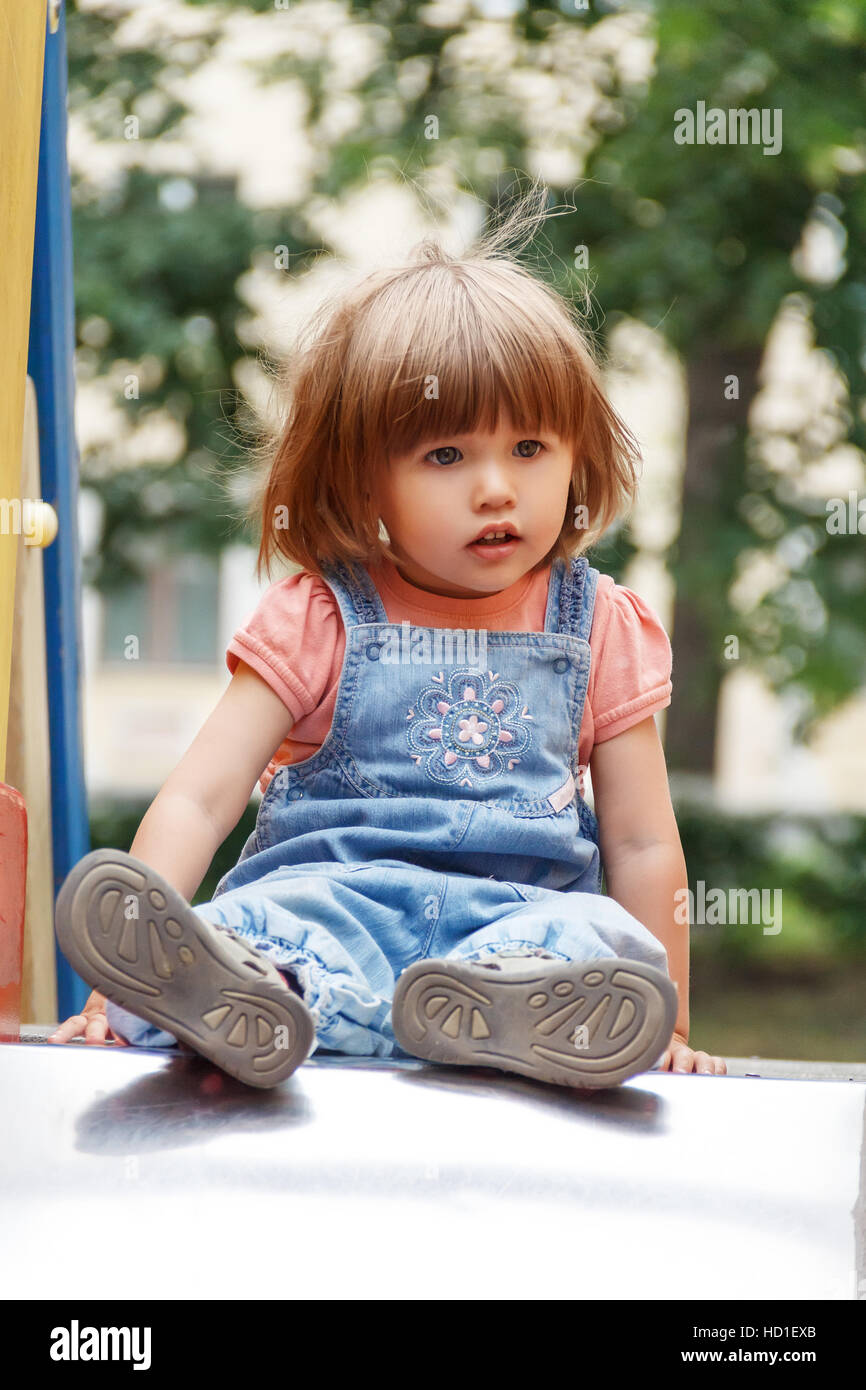 Baby sitting on hutches at the playground with disheveled hair Stock Photo