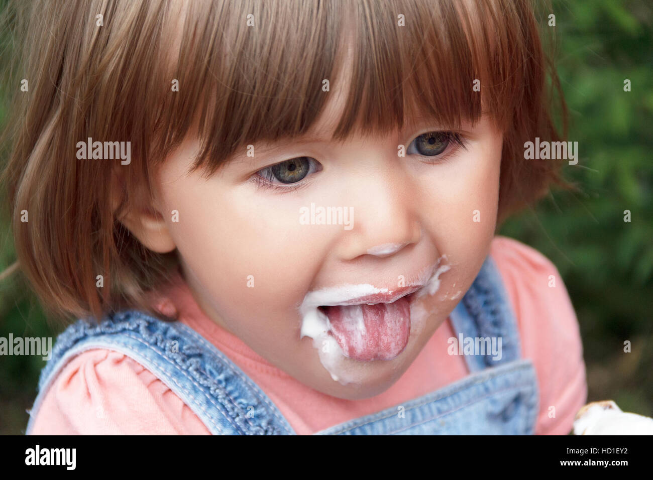 Cute baby girl are eating icecream in summer with put out tongue Stock Photo