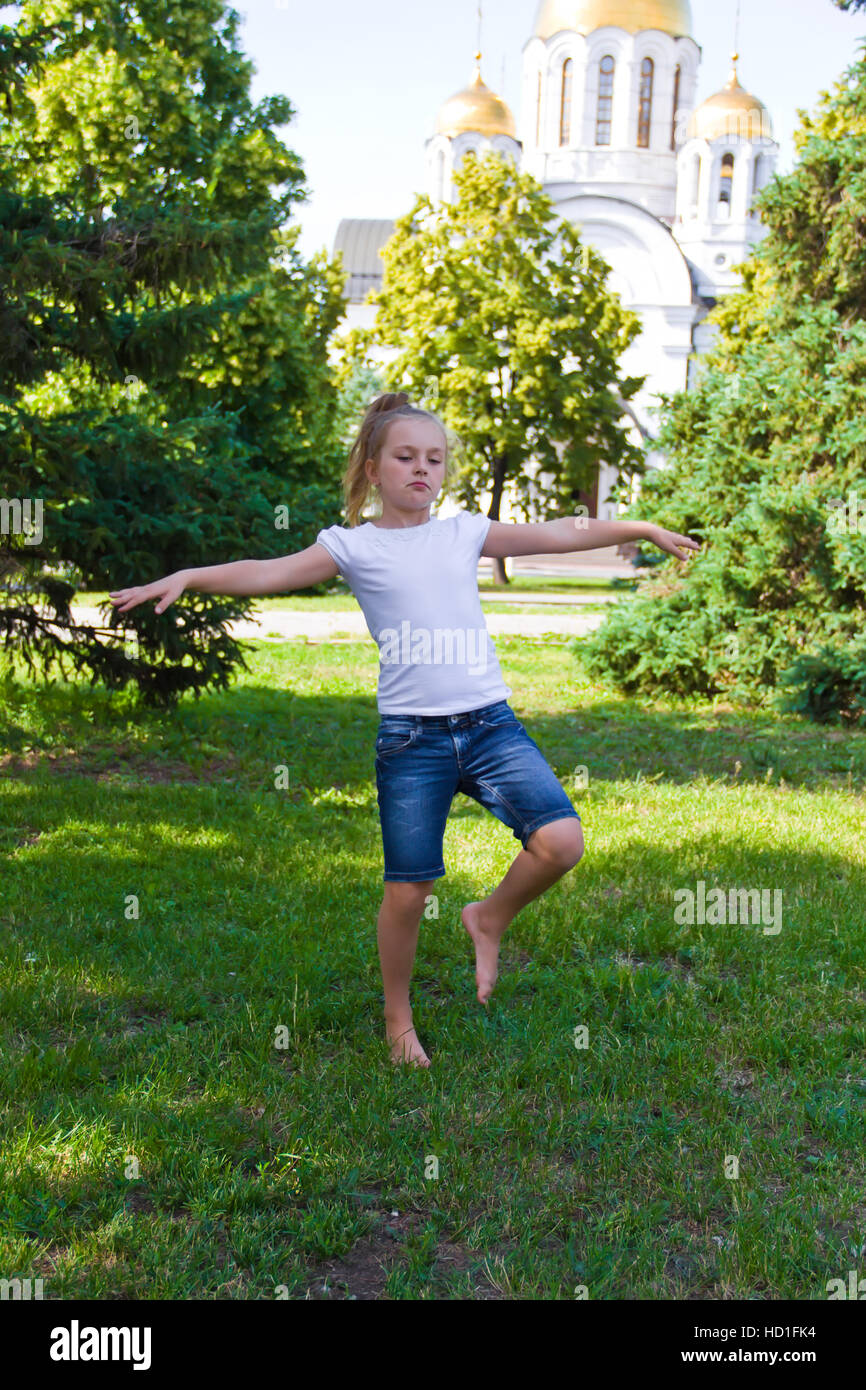 Cute girl with blond hair jumping on one leg Stock Photo