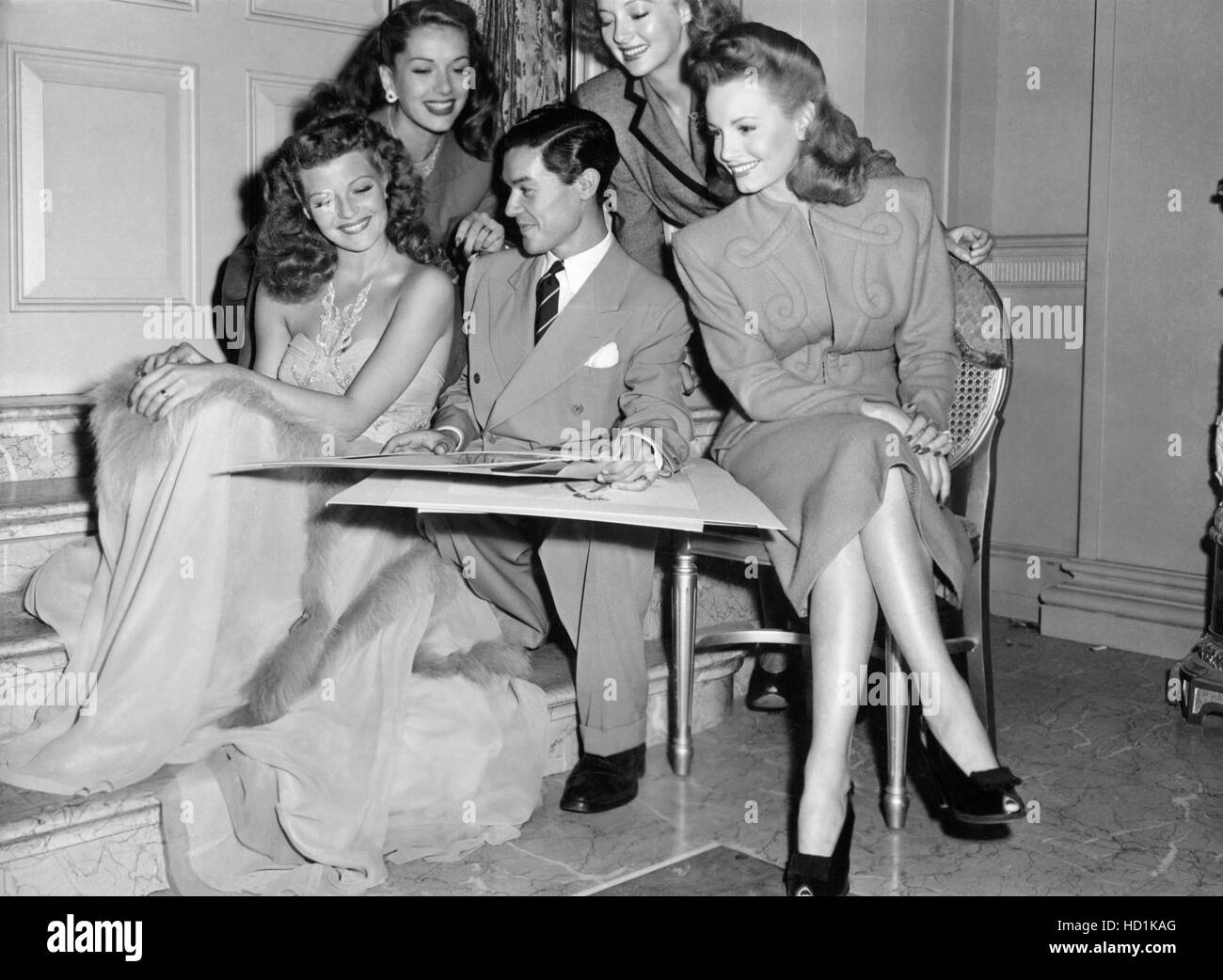 Columbia Pictures' costume designer, Jean Louis, shows sketches to actresses Rita Hayworth, Jinx