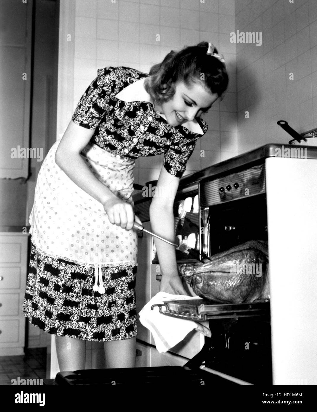 Joan Fontaine at home cooking a turkey, 1938 Stock Photo
