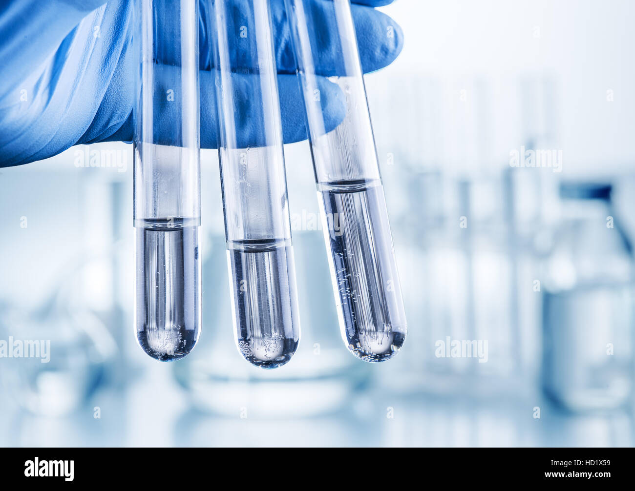 Laboratory beakers in analyst's hand in plastic gloves. Stock Photo