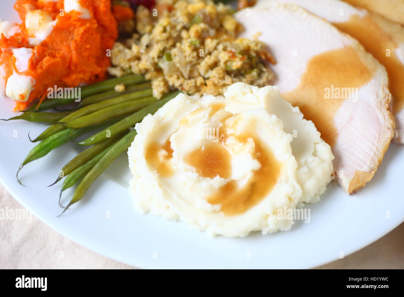 Thanksgiving meal with turkey, mashed potatoes, stuffing, green beans and yams with marshmallows and gravy Stock Photo