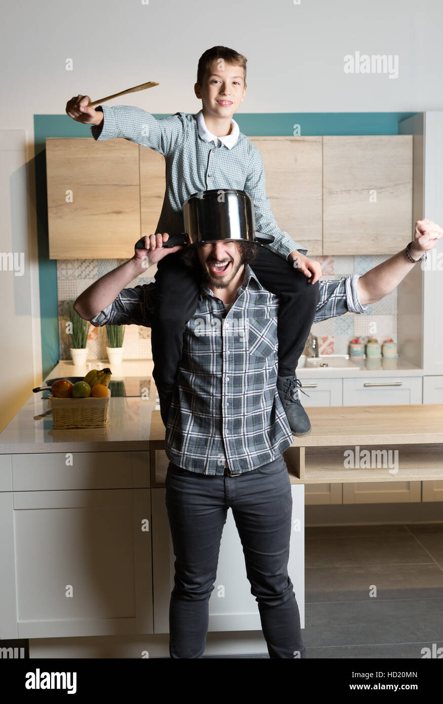 Handsome young father besidet the kitchen table holding his son on his shoulders Stock Photo