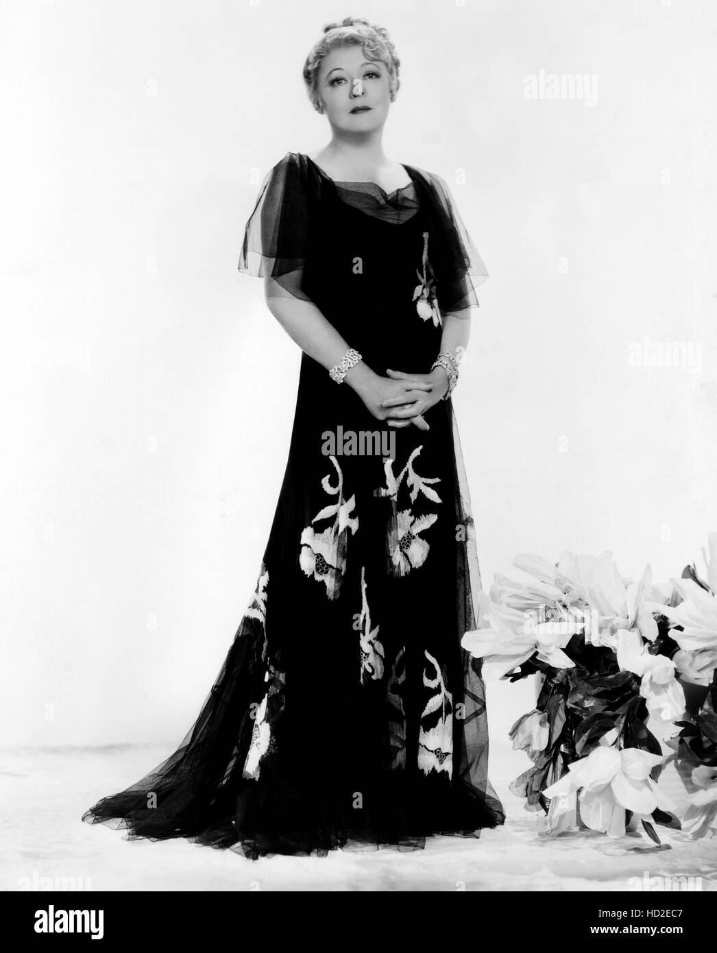 Mary Boland modeling black satin embroidered gown with tulle overlay