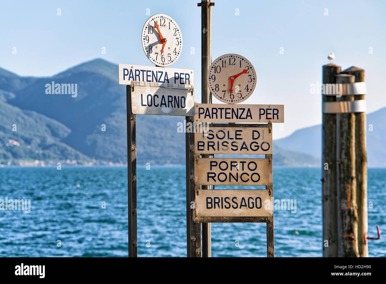 Clock at the Pier at the promenade in Ascona luxurious resort on Lake Maggiore, of Ticino canton in Switzerland. The letterings on the sings under the Stock Photo