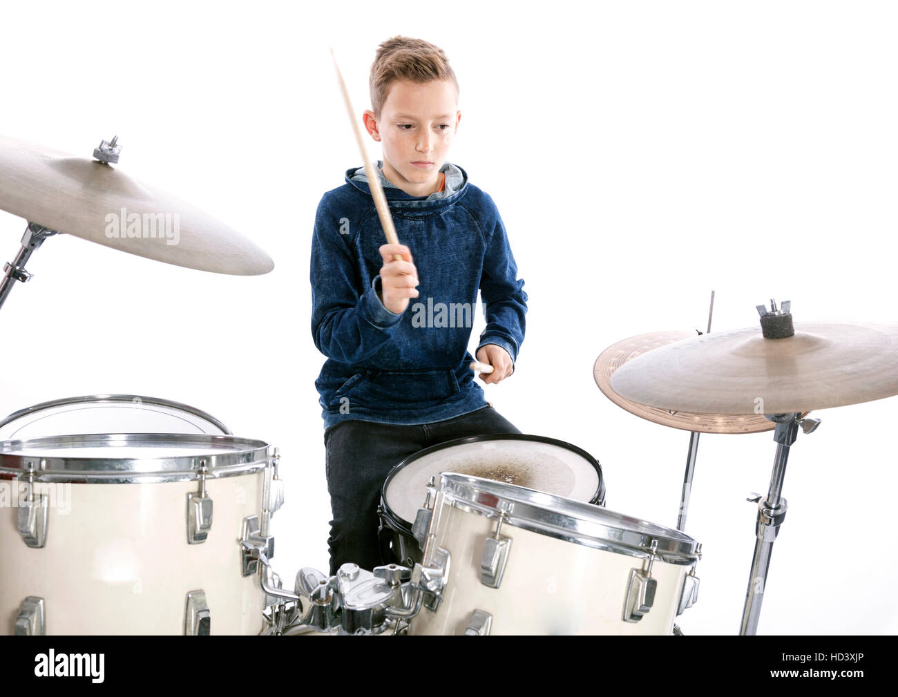 teenage boy behind drum kit in studio against white background Stock Photo
