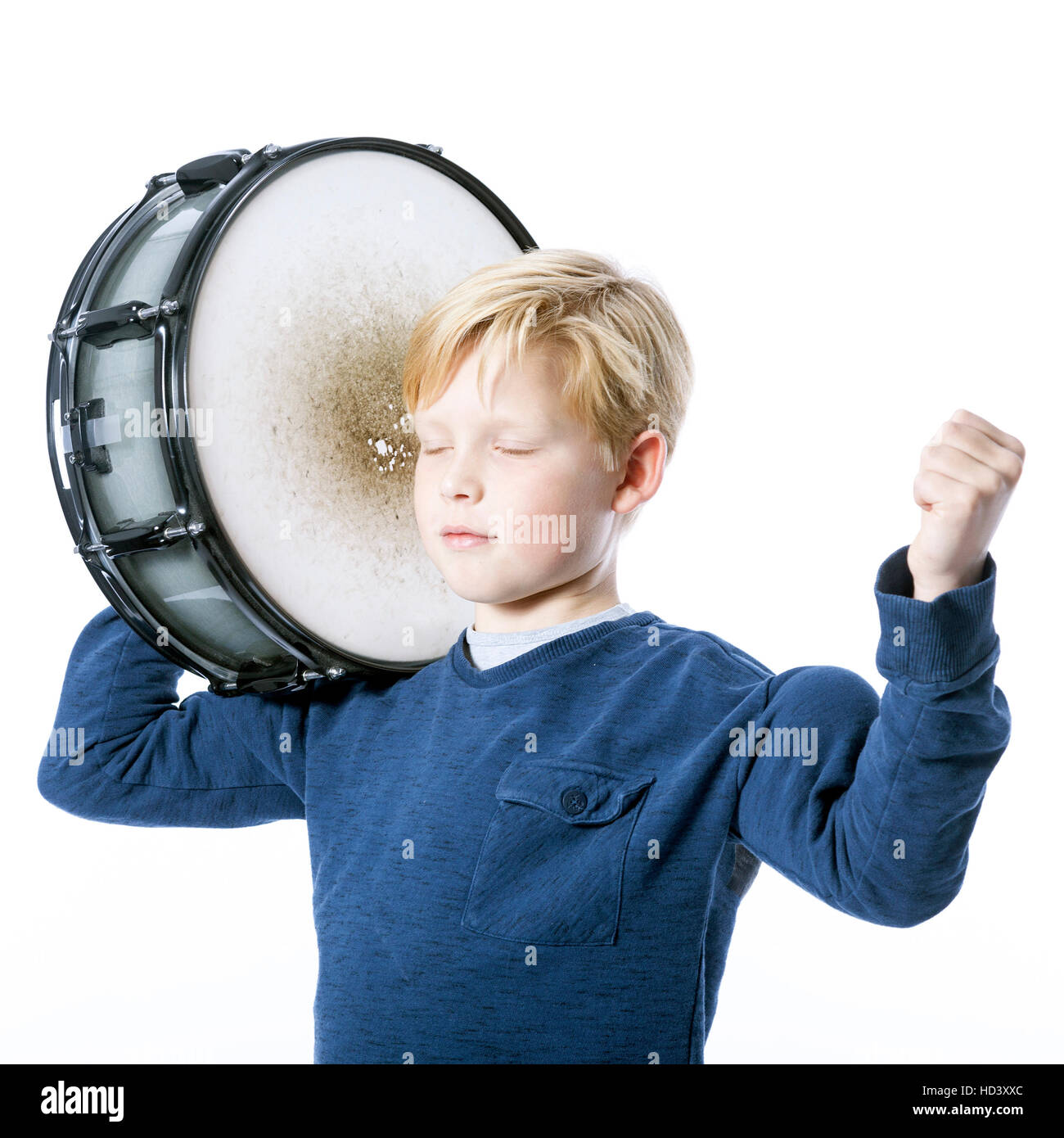 young blond boy with drum against white background in studio shows muscle and closed eyes Stock Photo