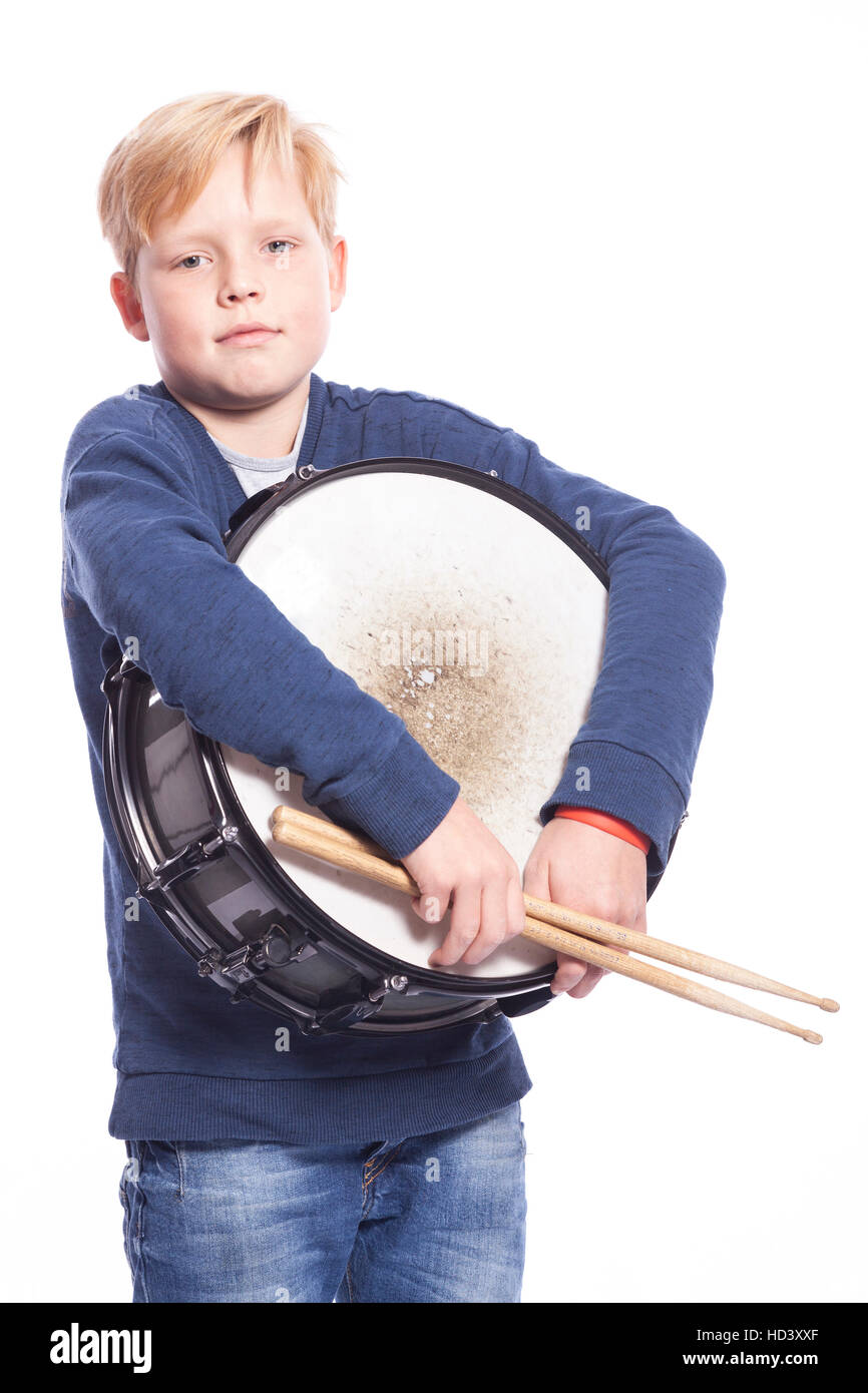 young blond boy in blue outfit holds drum against white background in studio Stock Photo