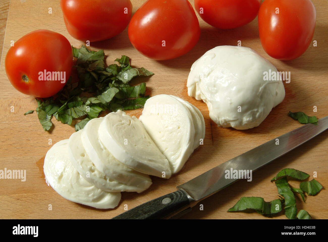 Buffalo Mozzarella cheese on a chopping board with fresh tomatoes Stock
