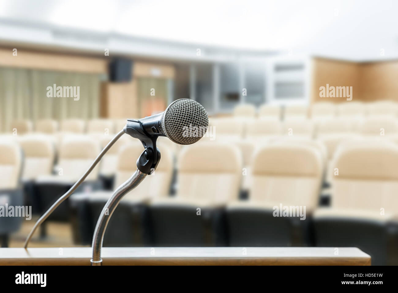Microphone stand on podium with abstract blur photo of conference hall or seminar room in background. Business seminar concept. Stock Photo