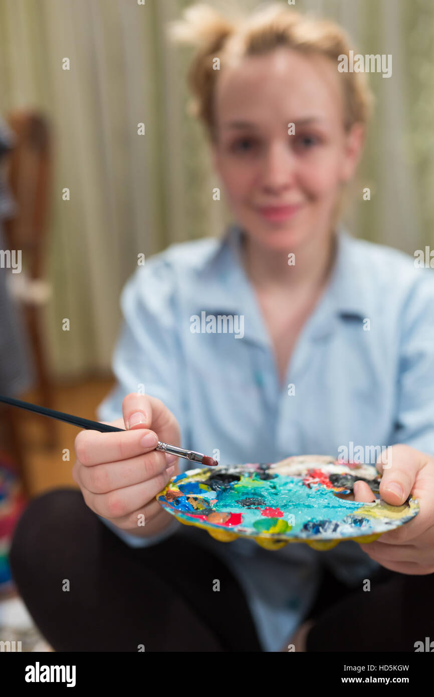 Smiling girl paints with oil colors in Stock Photo Alamy