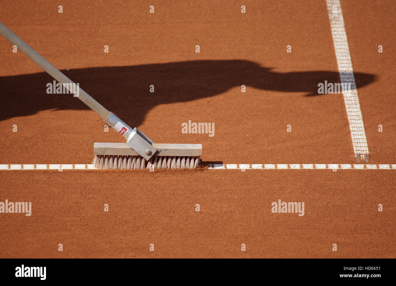 Shadow of a groundsman sweeping the baseline on a tennis court Stock Photo