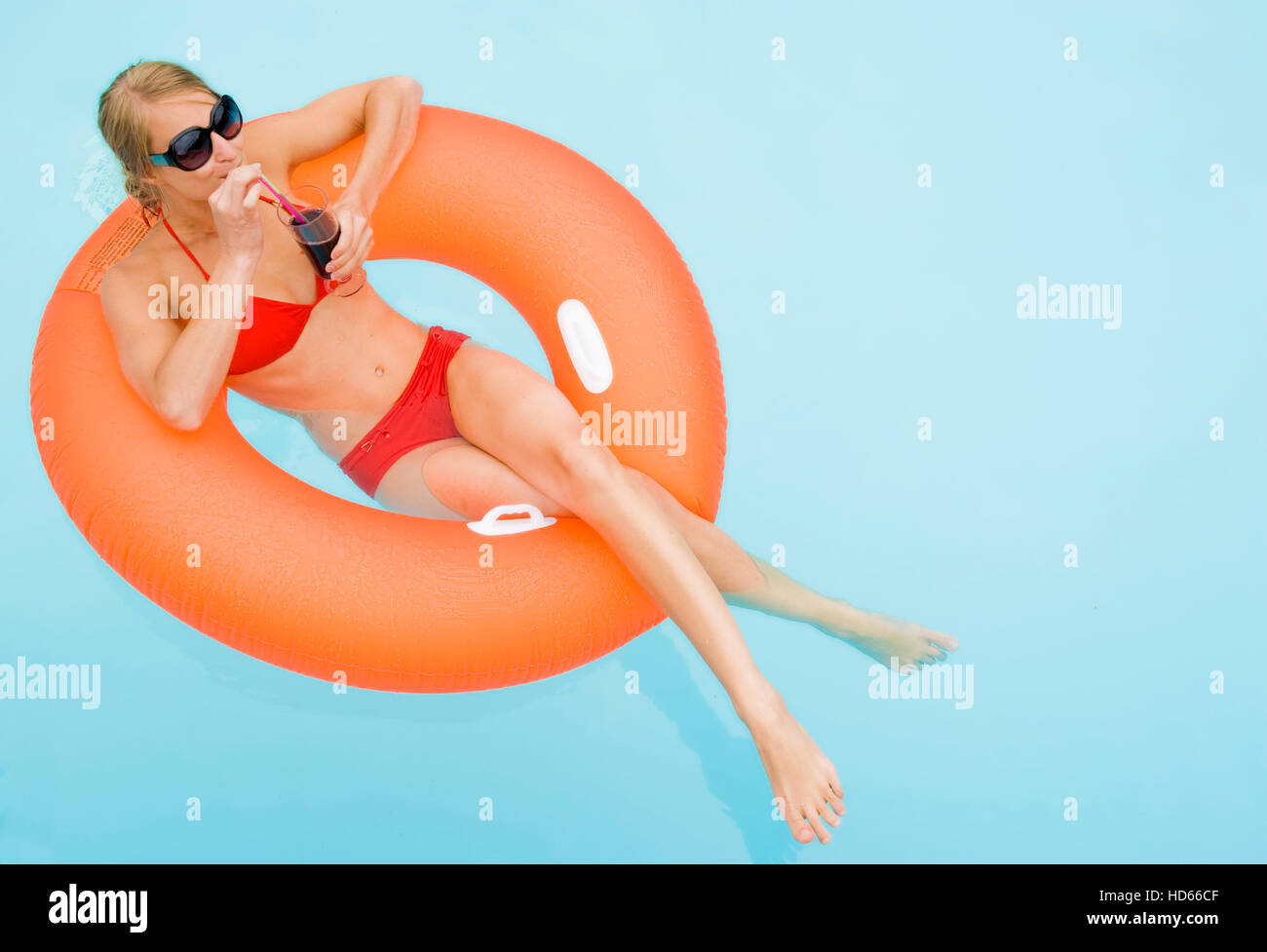 Young, attractive woman drinking a cocktail in a swimming pool Stock Photo