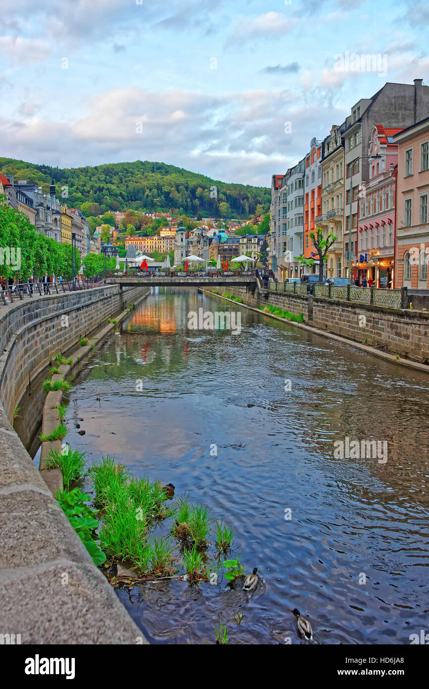 Karlovy vary, Czech republic - May 5, 2014: Tepla River embankment and St Mary Magdalene Church in Karlovy Vary, Czech republic. People on the backgro Stock Photo